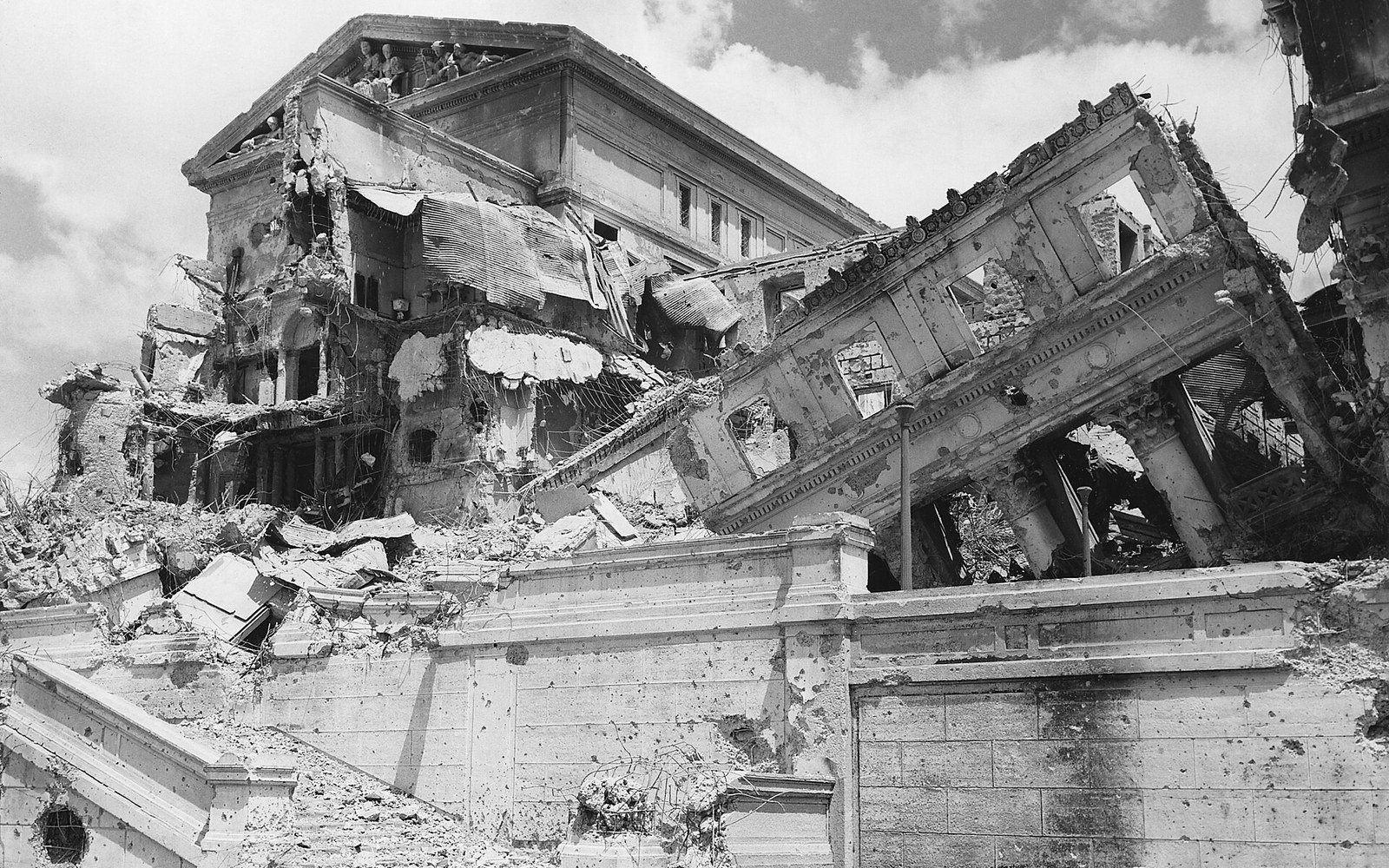 A collapsed multi-story building with shattered walls and exposed interior floors