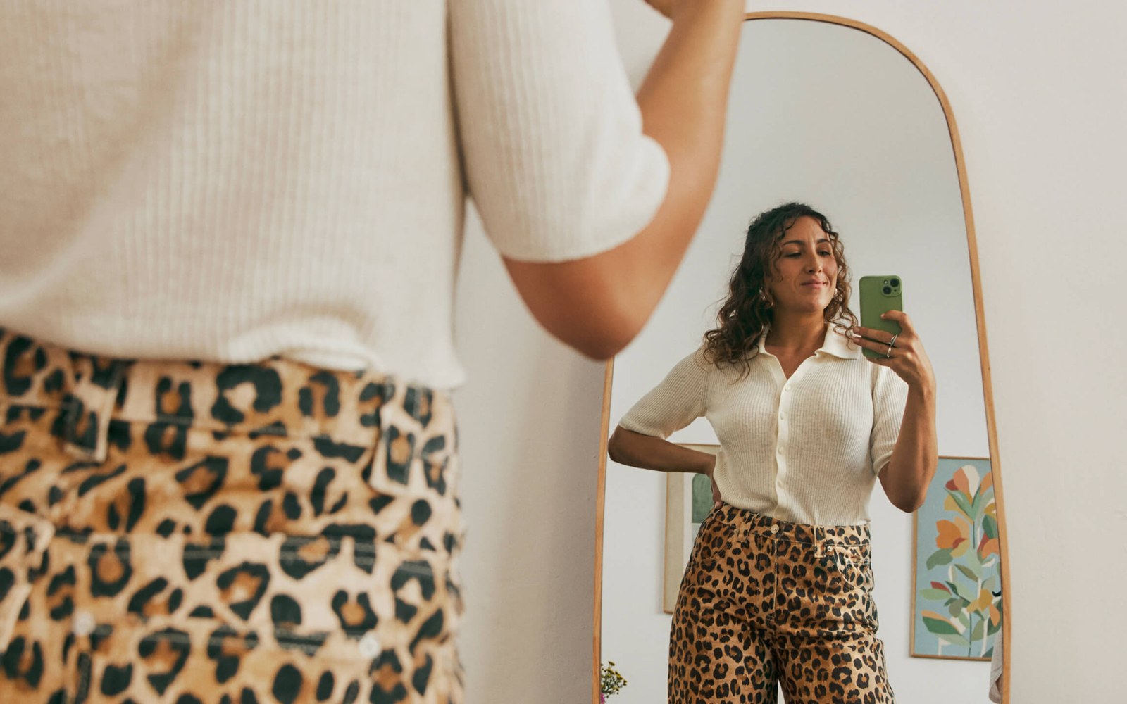 Woman in leopard-print pants takes a mirror selfie with her phone